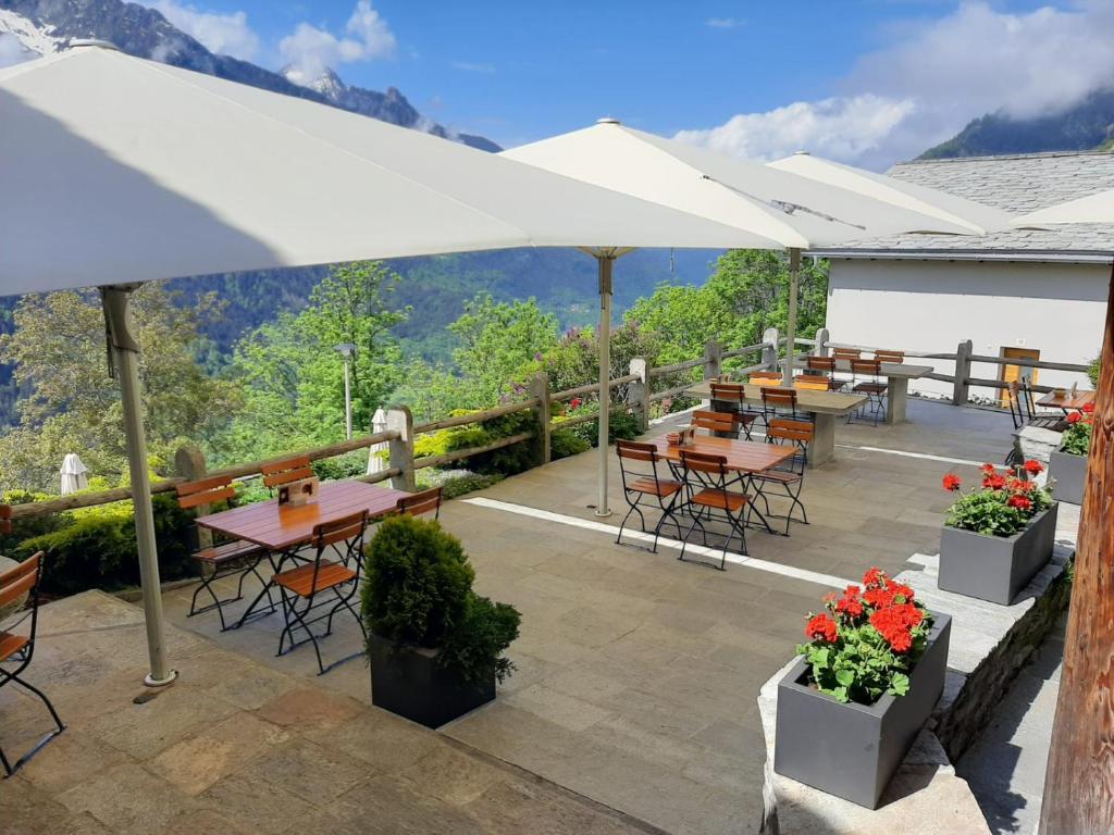 a patio with tables and chairs with mountains in the background at Hotel Stüa Granda in Soglio