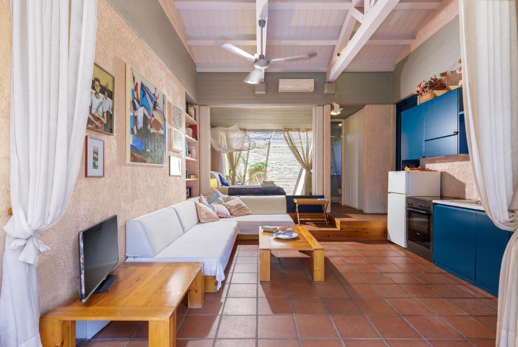 uma sala de estar com um sofá branco e uma televisão em Barbati Beach Art House em Barbati