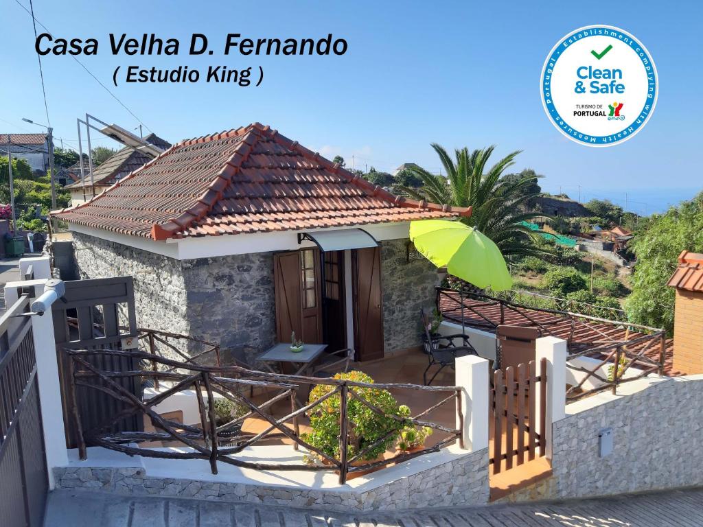 a small house with a green umbrella in front of it at Casa Velha D Fernando e Casa Avó Augusta in Ribeira Brava