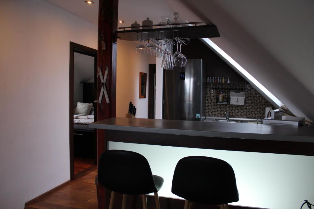 eine Küche mit einer Bar mit zwei schwarzen Stühlen in der Unterkunft BERNAT apartman in Vrútky