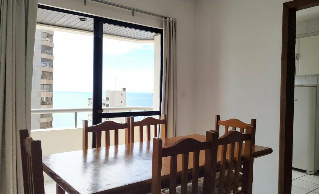 a dining room with a table and a large window at Residencial Chanel in Balneário Camboriú