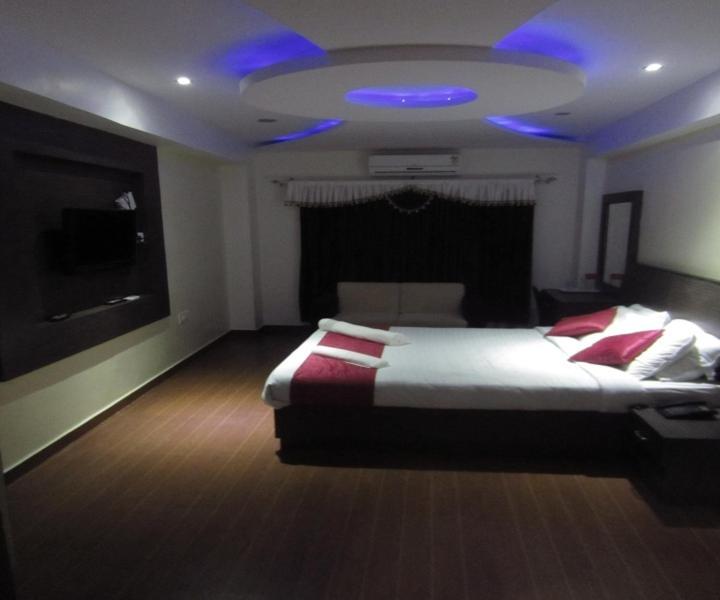 1 dormitorio con 1 cama grande y techo azul en Hotel MB International, en Mysore