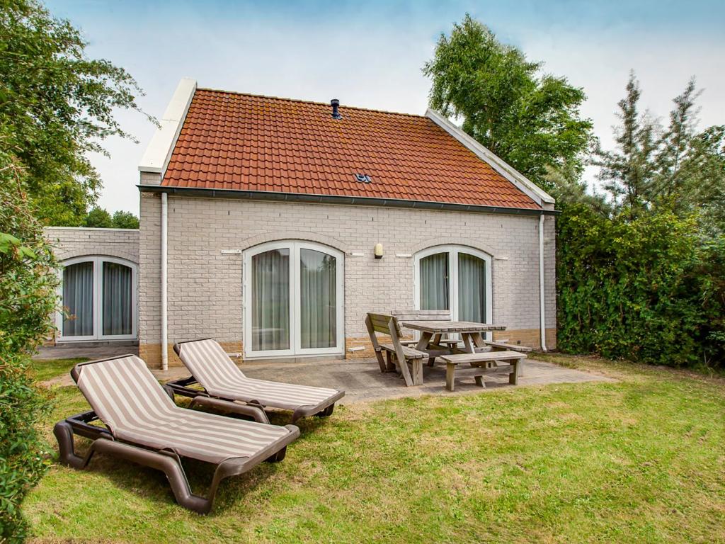 a patio with two chairs and a table and benches at Holiday Home Citta Romana-1 by Interhome in Hellevoetsluis