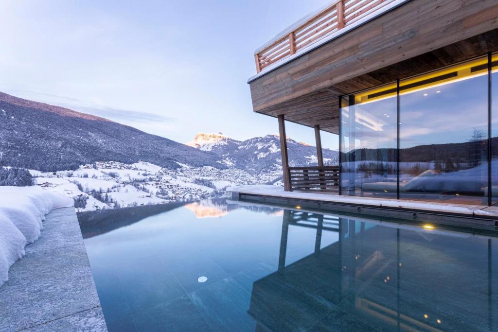 a house on a mountain with a swimming pool at Hotel Niblea Dolomites in Ortisei