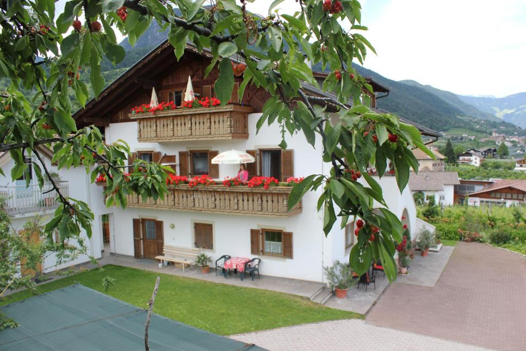 Cette maison blanche dispose d'un balcon orné de fleurs rouges. dans l'établissement Residence Rebgut, à Tesimo