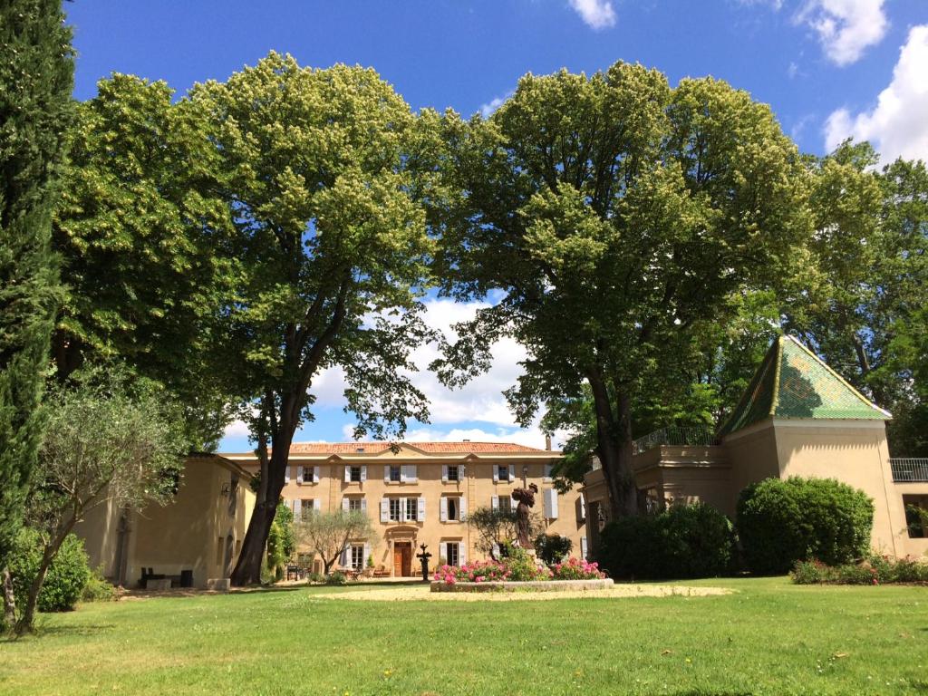 a building with trees in front of a yard at Château Rieutort Gîtes in Saint-Pargoire