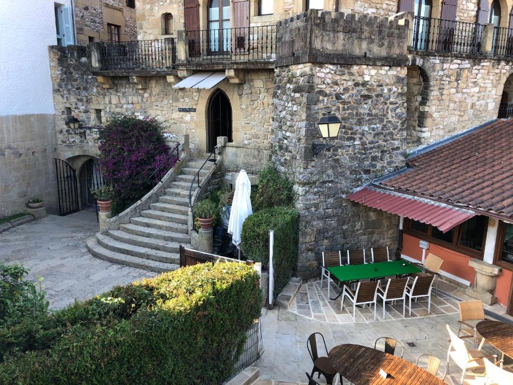 - un bâtiment en pierre avec des escaliers, une table et des chaises dans l'établissement Hotel Palacio Obispo, à Fontarrabie
