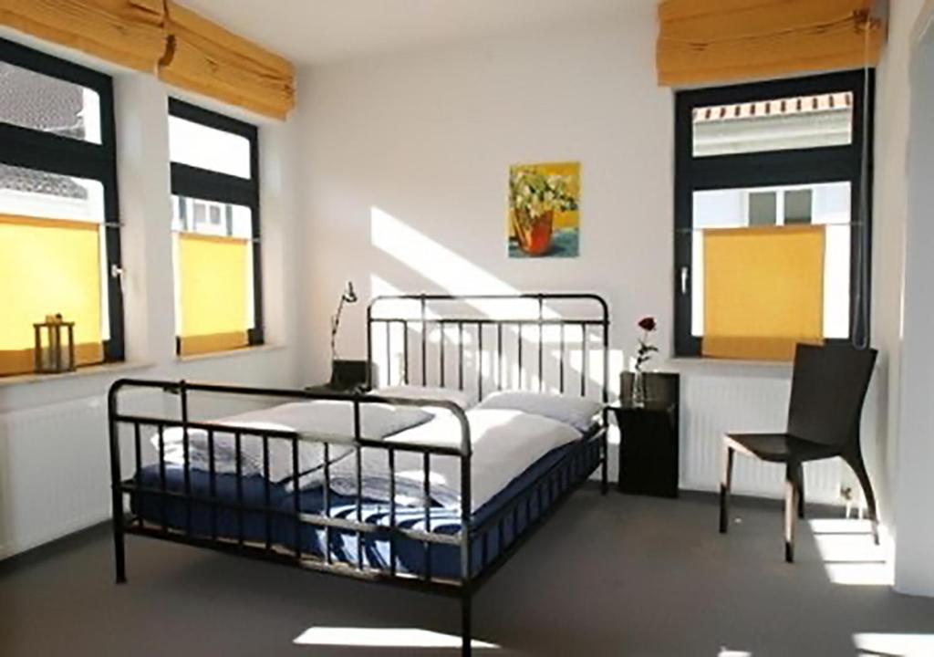 - une chambre avec un lit, une chaise et des fenêtres dans l'établissement Ferienwohnung KLÜN's, à Jever