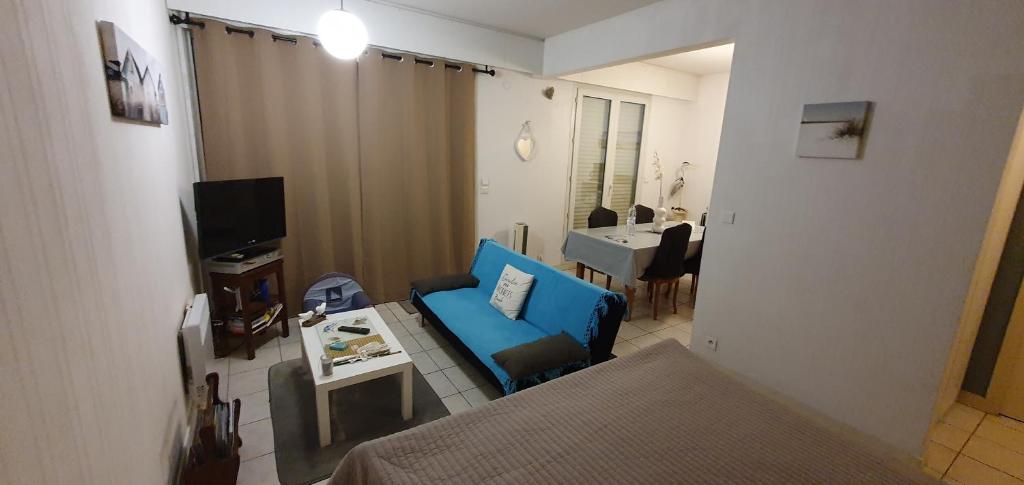Cette petite chambre comprend un lit et une chaise bleue. dans l'établissement Location Royan aperçu mer wifi, à Royan