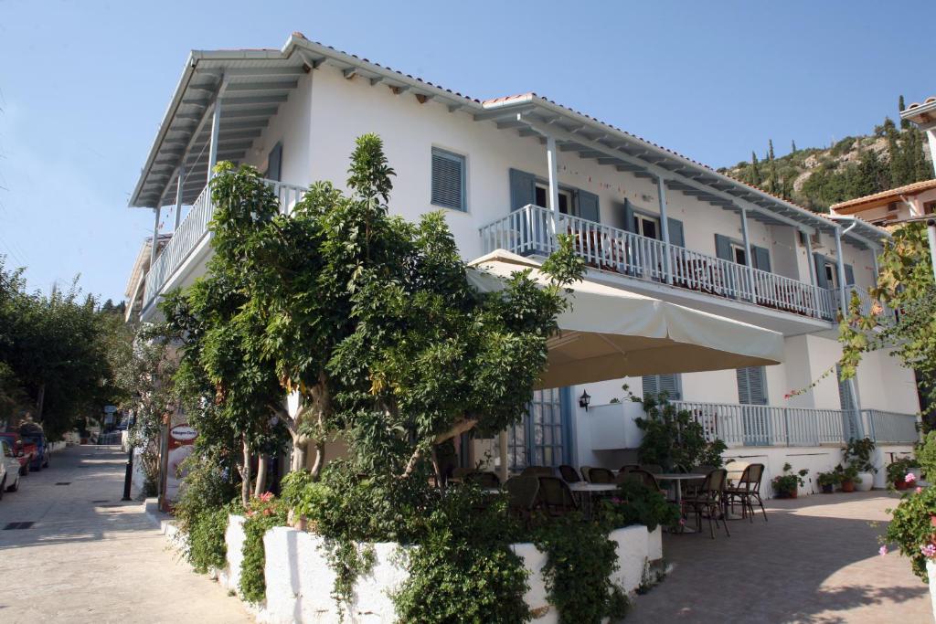 a large white building with a balcony on a street at Elena Rooms in Agios Nikitas