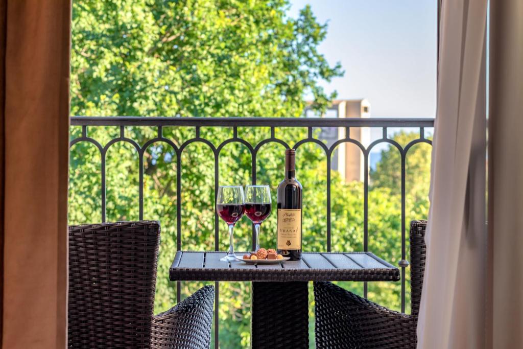 a table with two glasses of wine on a balcony at Luxury Apartments Queen in Petrovac na Moru