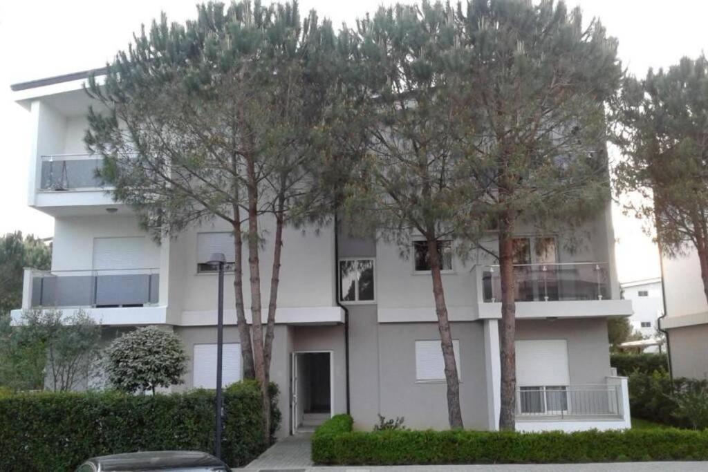 un bâtiment blanc avec des arbres devant lui dans l'établissement Luna`s beachfront apartment in Residence Primavera Lalzit, à Durrës