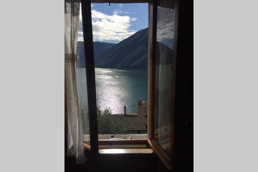 una finestra con vista sul lago e sulle montagne di Nel set di piccolo mondo antico Villa Viola a Valsolda