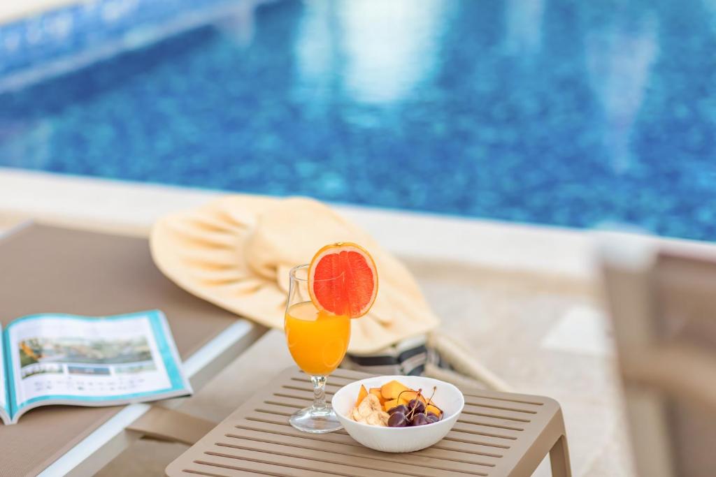 a drink and a bowl of fruit on a table next to a pool at Luxury Apartments Queen in Petrovac na Moru