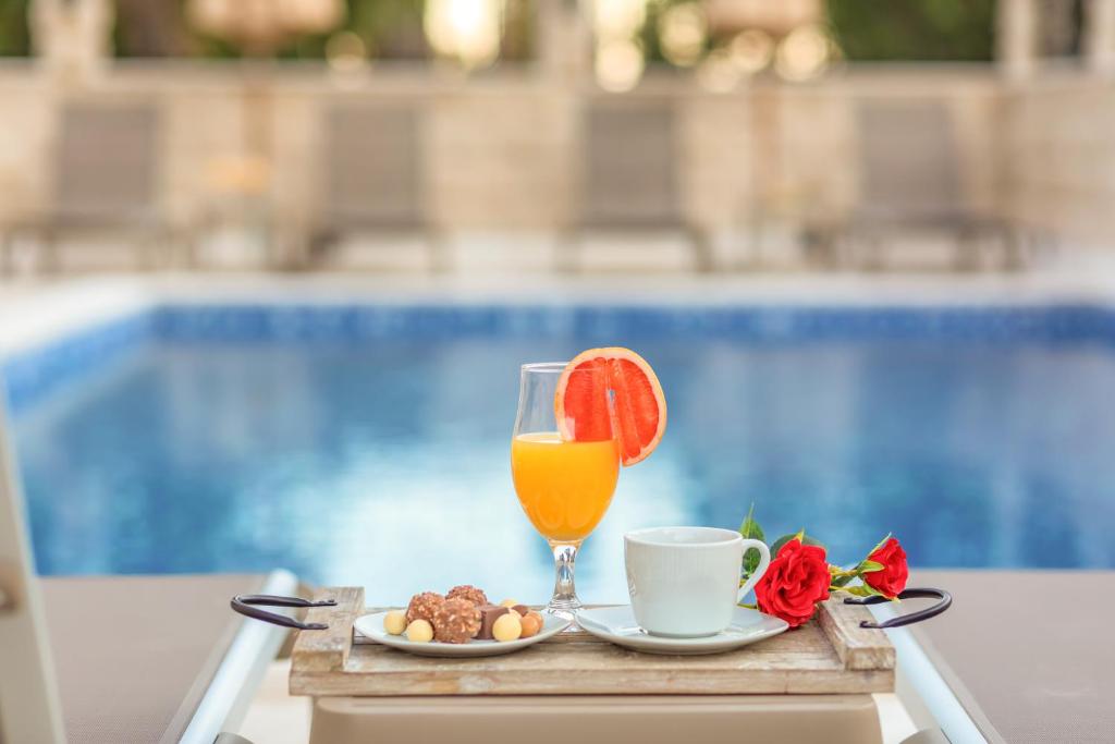 una mesa con un vaso de zumo de naranja y un plato de comida en Luxury Apartments Queen, en Petrovac na Moru