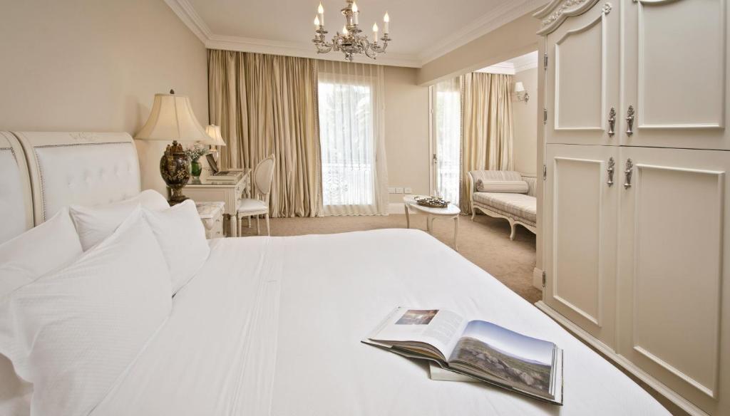 Un dormitorio con una cama blanca con un libro. en Hotel Sainte Jeanne en Mar del Plata