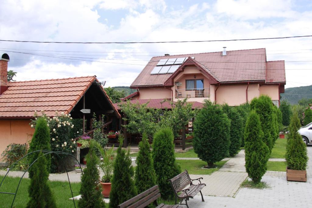 a house with a bench and trees in front of it at Pensiunea Andreea in Baia de Fier