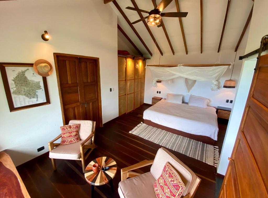 1 dormitorio con 1 cama y sillas en una habitación en Mountain Farmhouse Retreat with incredible Views en Minca
