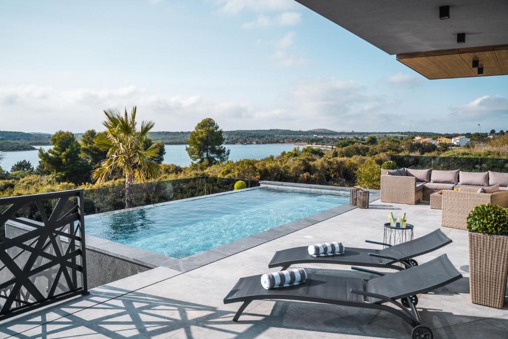 einen Außenpool mit Stühlen und Blick auf das Wasser in der Unterkunft Villa Vie in Medulin