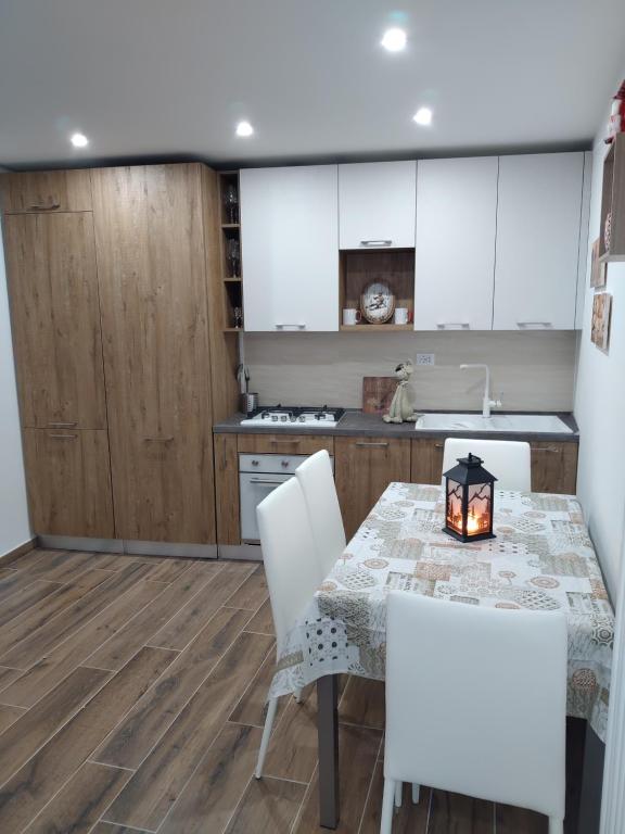 a kitchen with a table and white chairs at Piccolo Paradiso in pieno centro Rivisondoli in Rivisondoli