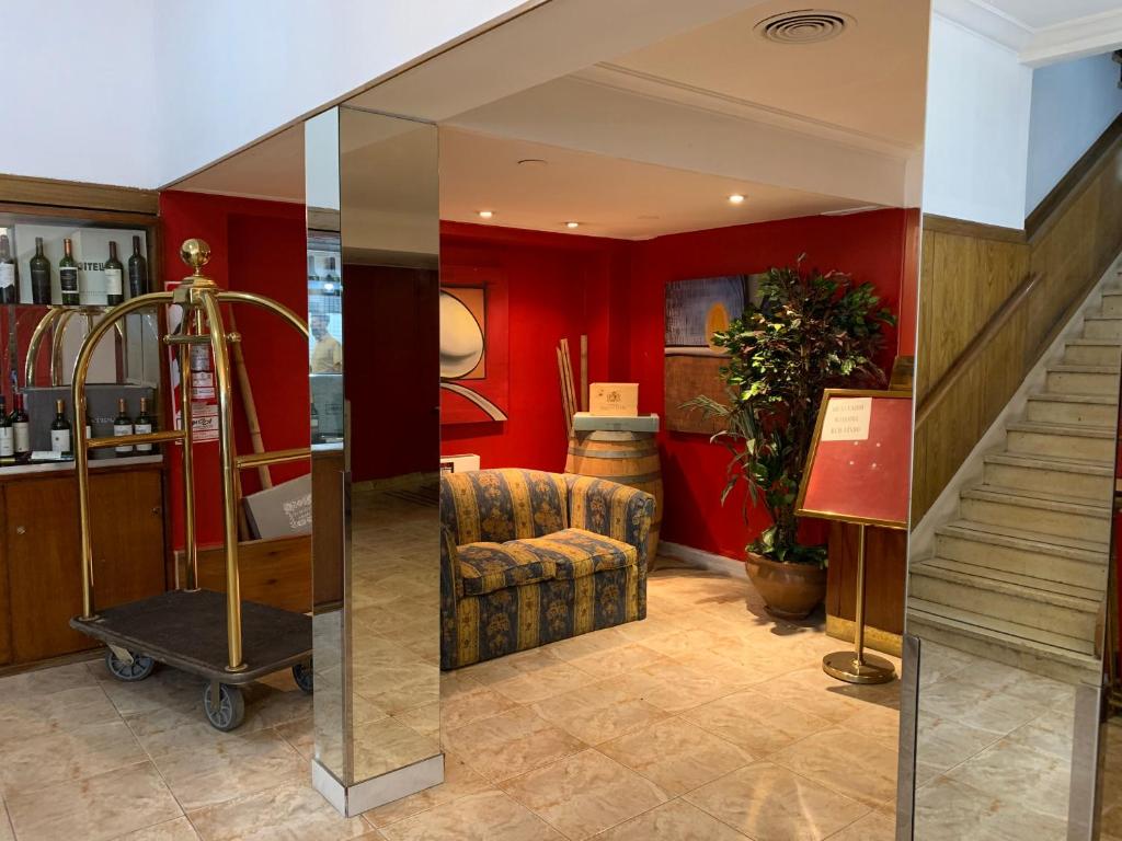 una hall con pareti rosse, una sedia e scale di Palace Hotel Mendoza a Mendoza