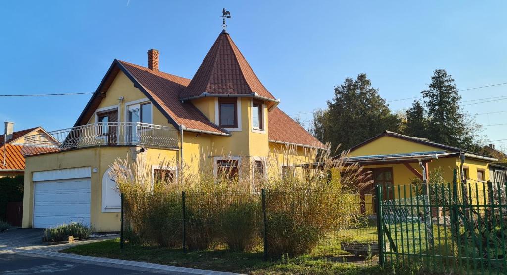 ein gelbes Haus mit braunem Dach in der Unterkunft Hajas Família Kiadó Szobák in Balatonmáriafürdő
