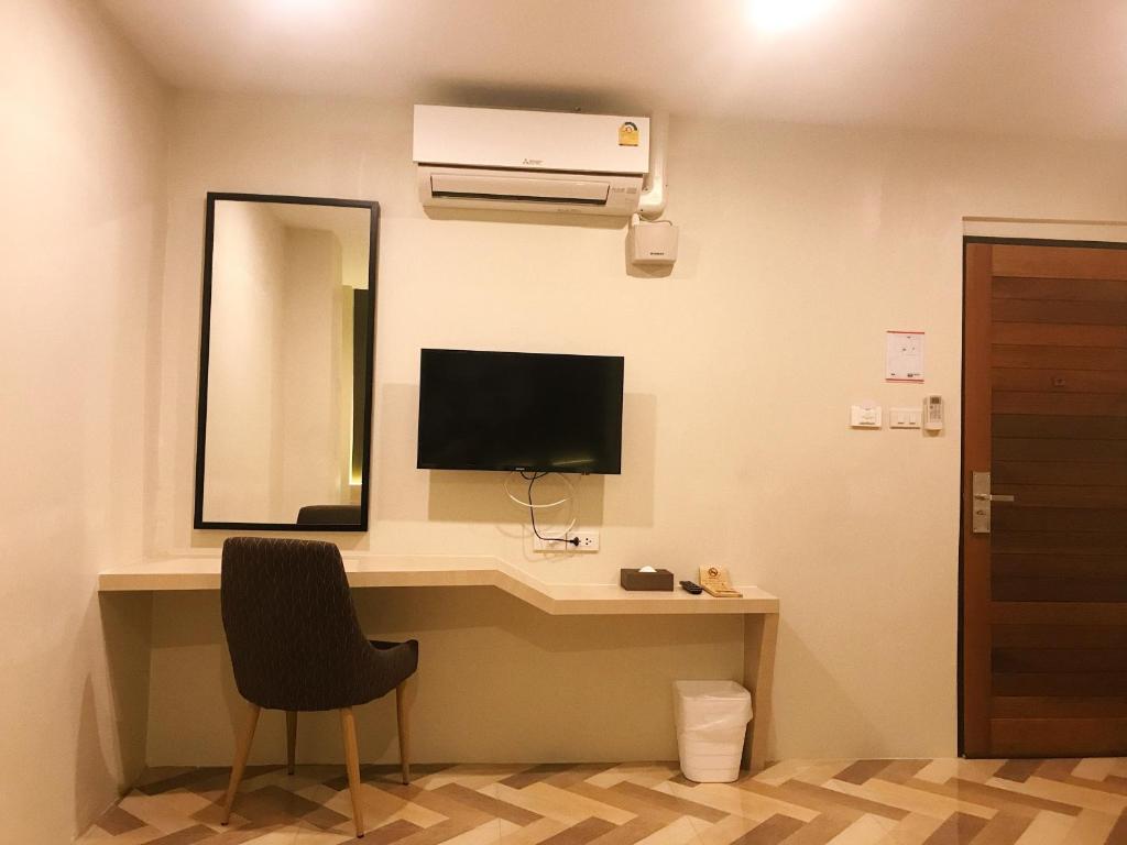 a room with a desk with a television and a mirror at SJ Miracle Hotel in Hat Yai