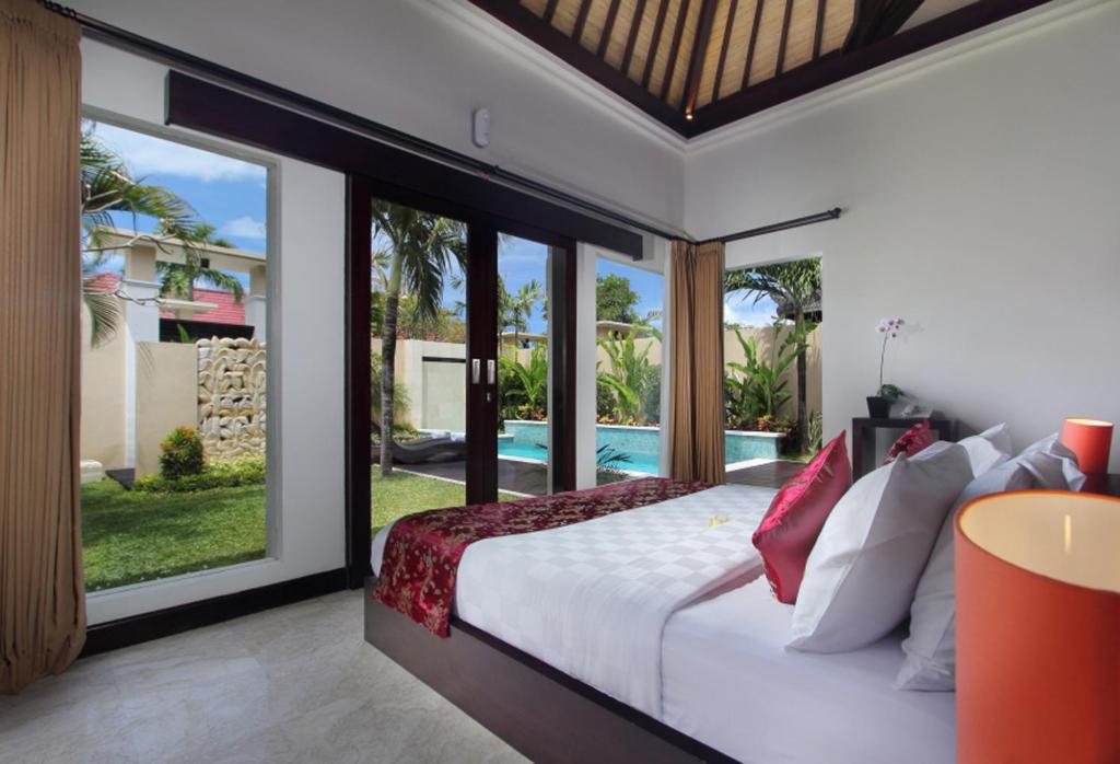 a bedroom with a bed and a view of a pool at RC Villas and Spa Bali in Seminyak