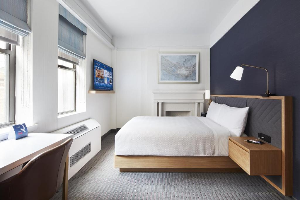 um quarto com uma cama, uma secretária e janelas em Club Quarters Hotel Times Square, New York em Nova York