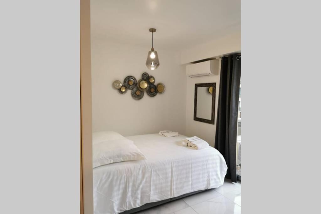 Schlafzimmer mit einem weißen Bett und einem Spiegel in der Unterkunft Cosy Studio 200 m from Nice Beach & Promenade des Anglais in Nizza