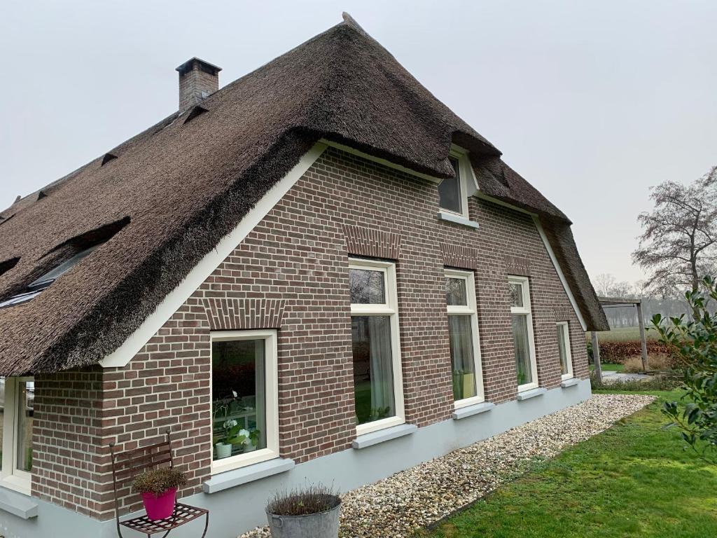 De Boerderij - Buitenplaats Ruitenveen, privé في Nieuwleusen: منزل من الطوب القديم مع سقف من القش