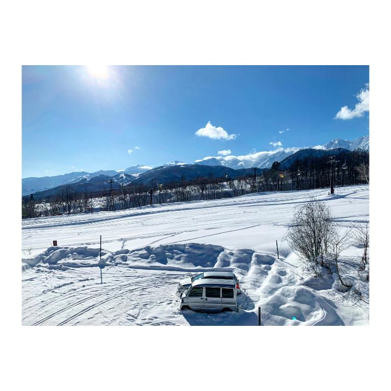 a car parked in a snow covered field at Sunshine Hakuba Ski-to-door by JAMSZ ROYALE in Hakuba