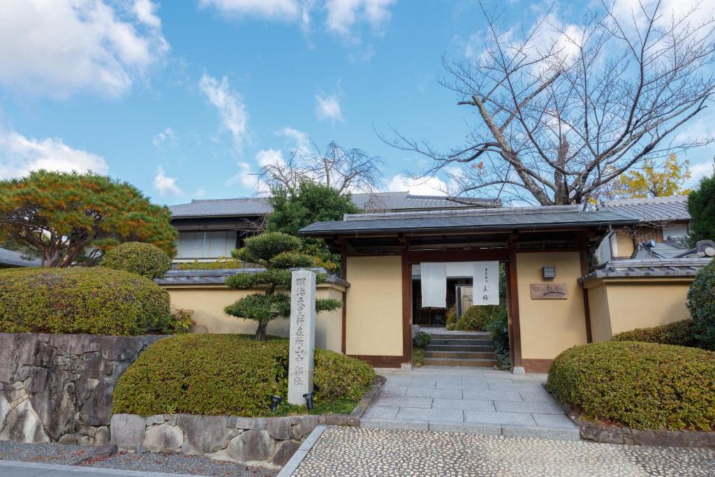 una casa con una puerta y arbustos delante de ella en Ranzan en Kyoto