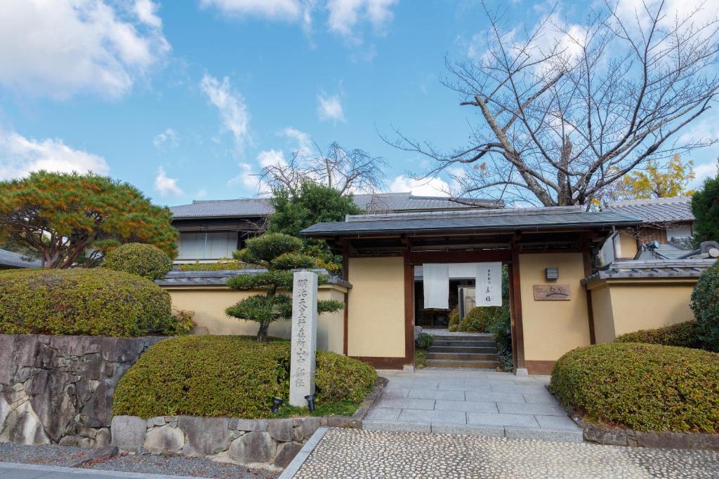 京都的住宿－藍贊旅館，前面有门和灌木的房子