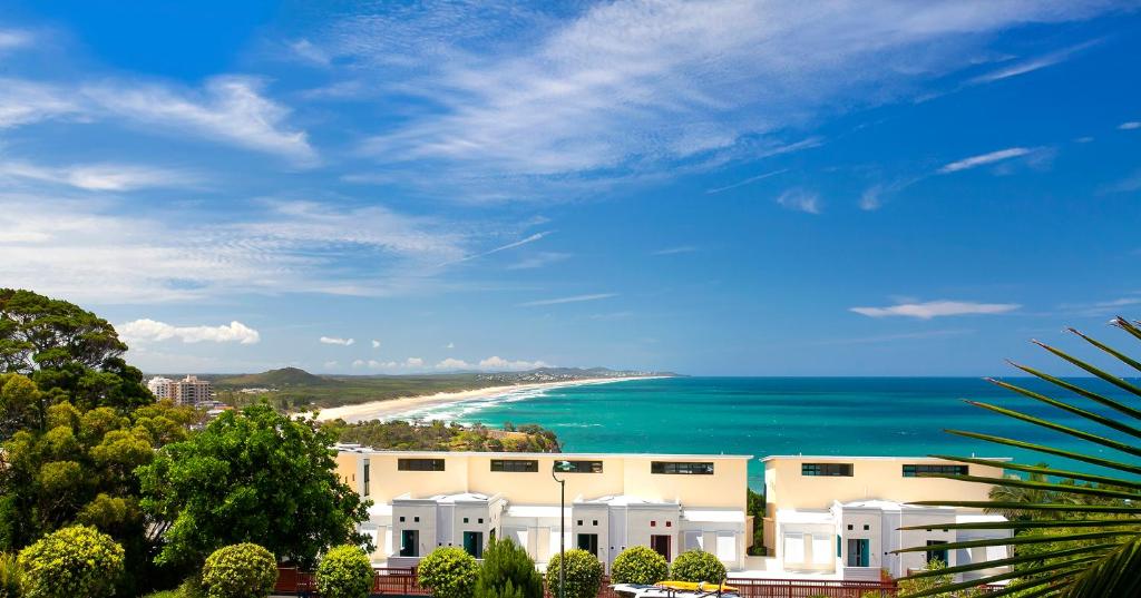 a view of a beach with a building and the ocean at The Point Coolum in Coolum Beach