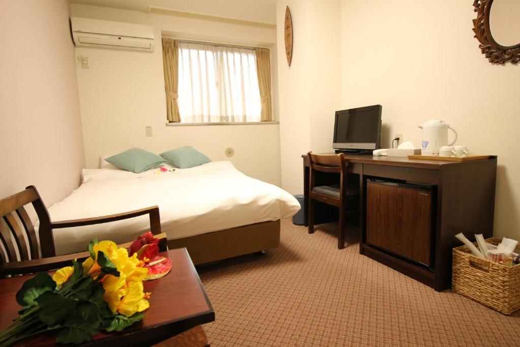 a hotel room with a bed and a desk and a television at Okubo Hotel Hawaii in Tokyo