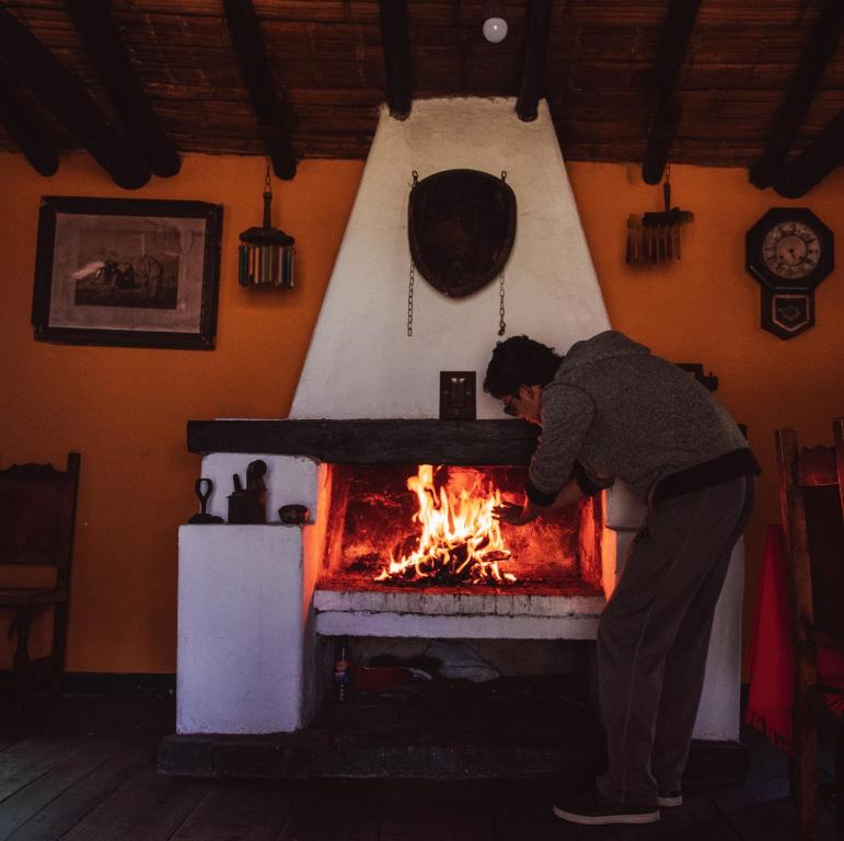 a man standing over a fire in a fireplace at Hotel y Centro de Convenciones Pueblito de Yerbabuena Paraíso Natural in Chía