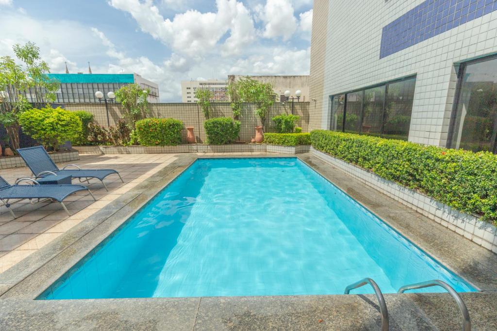 a swimming pool with blue water in front of a building at OYO Real Palace Hotel, Teresina in Teresina