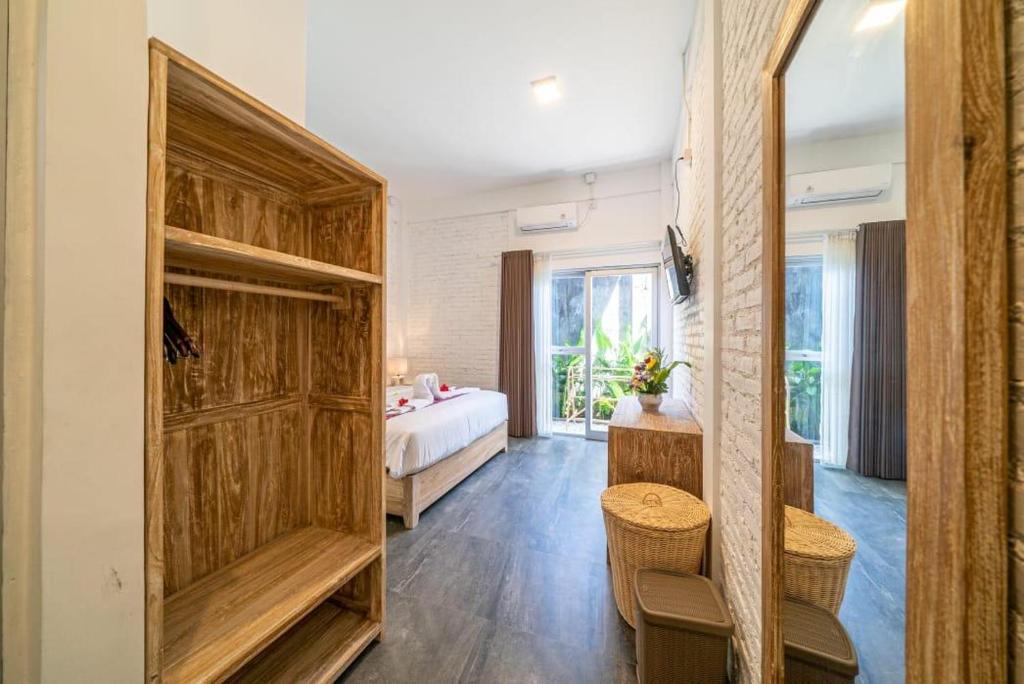 a bedroom with a bed and a large wooden closet at EUFORIA Guest House in Canggu