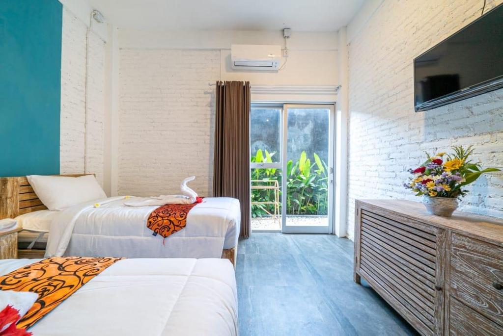 a hotel room with two beds and a television at EUFORIA Guest House in Canggu