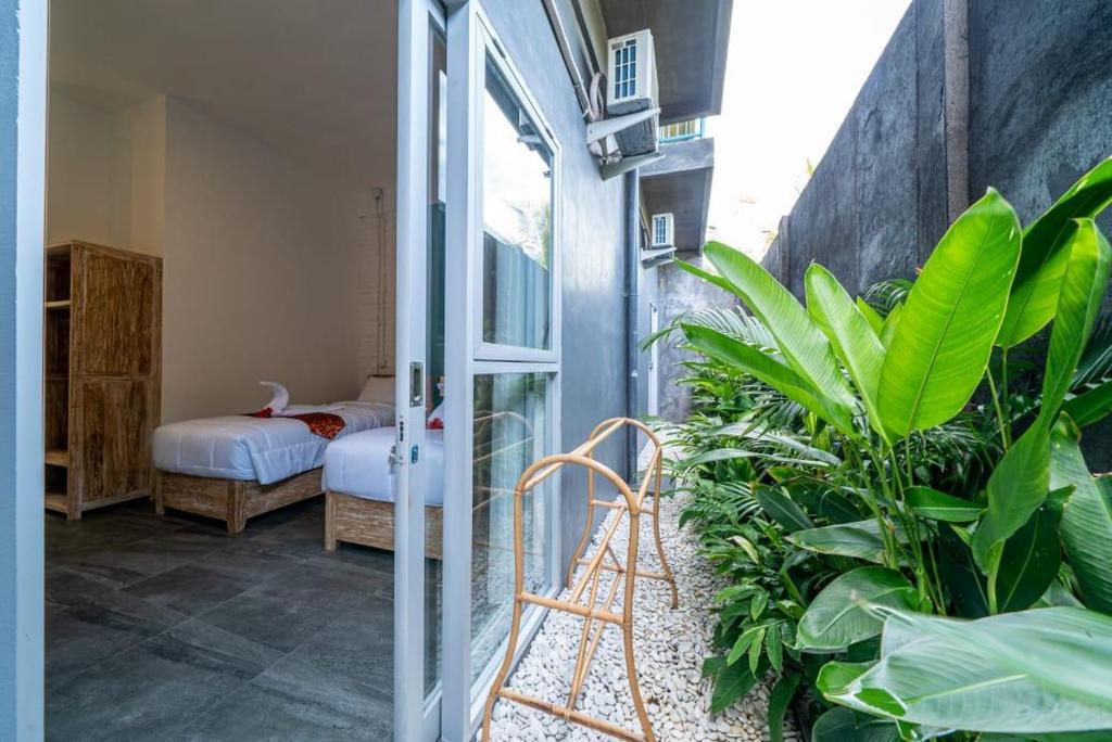 a room with a door and some plants and a bedroom at EUFORIA Guest House in Canggu
