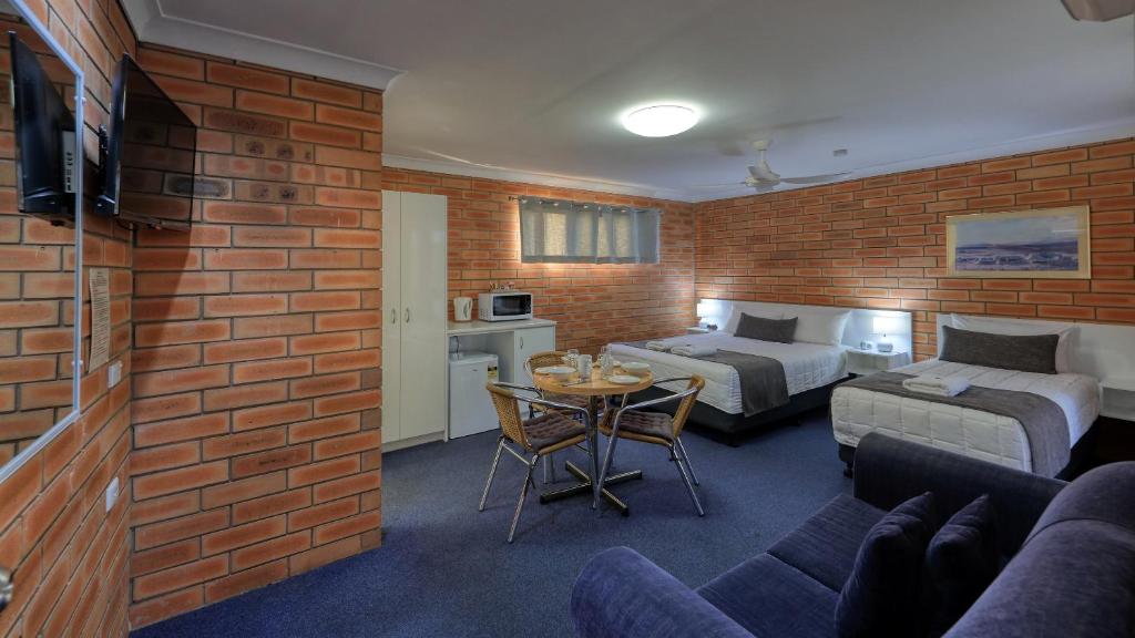 a hotel room with two beds and a table with a couch at Gunsynd Motor Inn in Goondiwindi