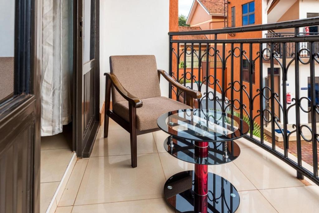 balcone con sedia e tavolo in vetro di Spacious apartment in secure Resort - 46 People a Kampala