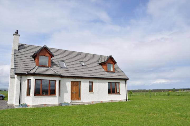 a white house with a gray roof on a green field at Ard Garraidh in Ardersier