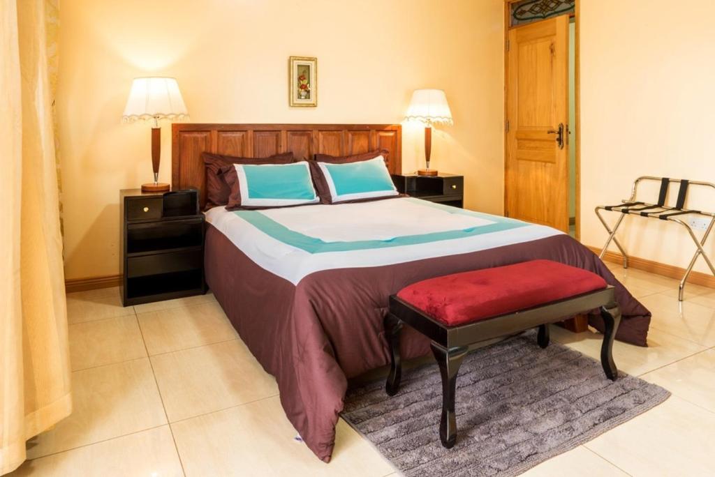 een slaapkamer met een groot bed en een rode bank bij Apartment in secure Resort - 46 People in Kampala