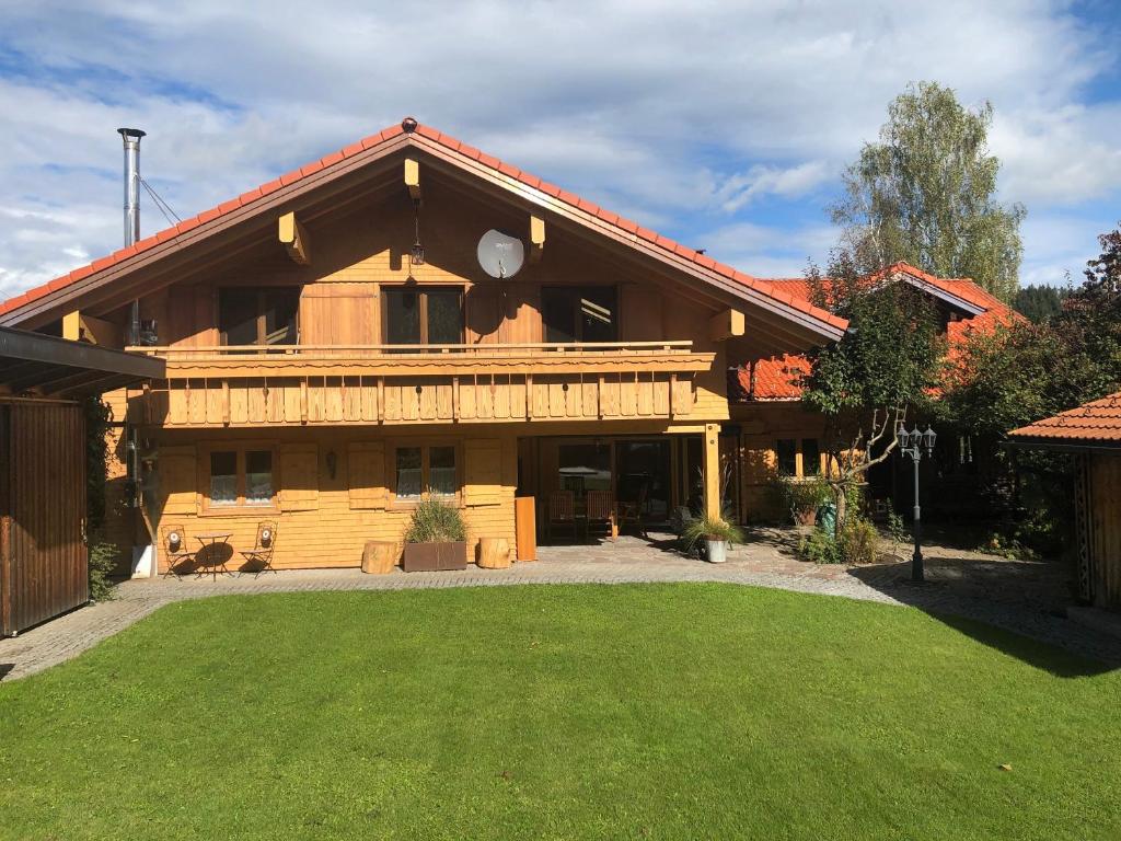 a large wooden house with a lawn in front of it at Monikas Ferienwohnung in Stiefenhofen