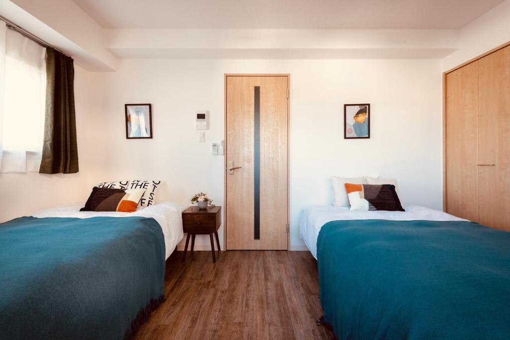 2 camas en una habitación de color azul y blanco en 谷町君星ホテル九条27, en Osaka