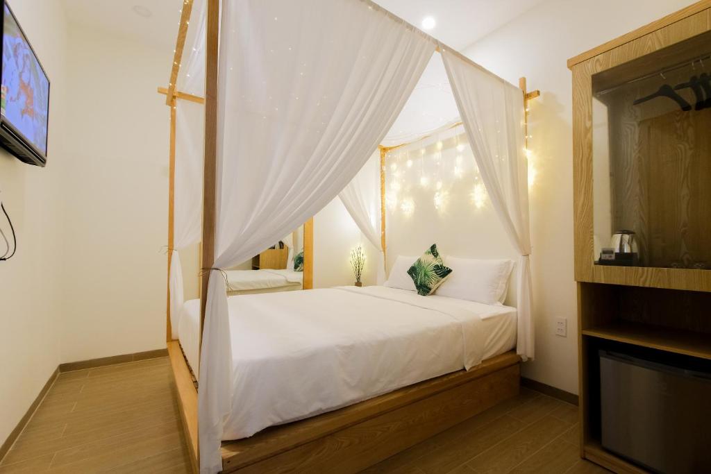 1 dormitorio con cama con dosel y cortinas blancas en ZELDA hotel en Xã Thang Tam