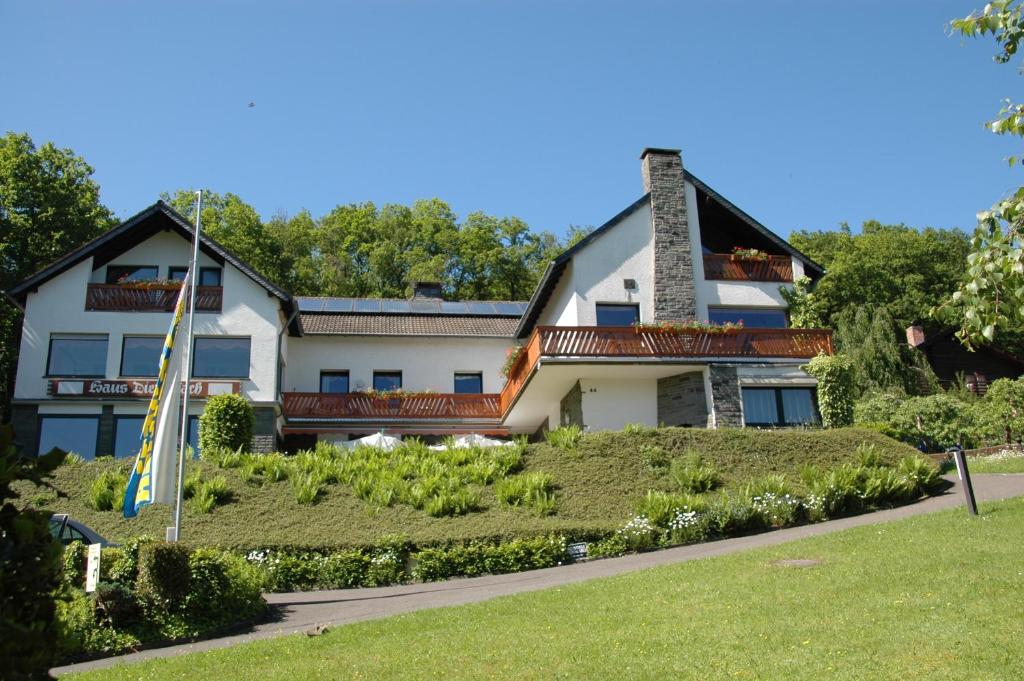 a large white house with a landscaping in front of it at Pension Haus Diefenbach in Heimbach