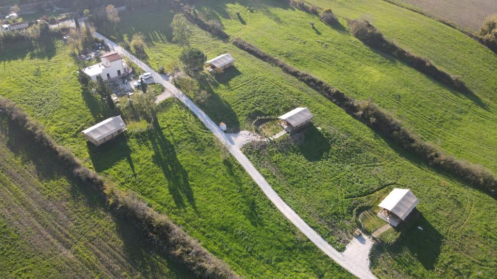 Glamping Tenuta San Pierino Agriturismo في روزينيانو ماريتيمو: اطلالة جوية على مزرعة في ميدان
